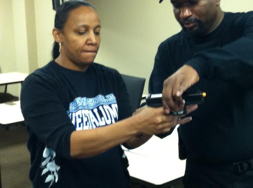 Instructor Leon S. Adams instructs a first time student on basic handgun fundamentals during Introduction to Handguns for Self Defense