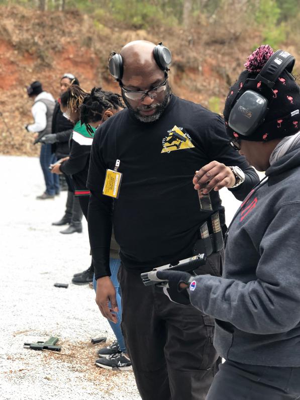 Female shooter on the firing line running practical shooting drills while being coached by instructors.